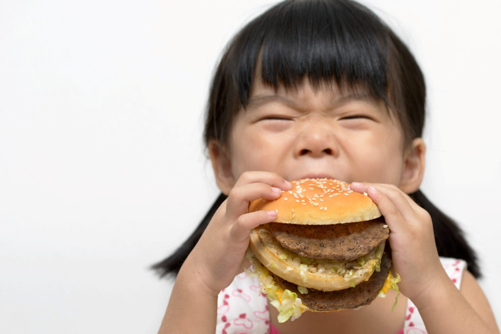 Kleines Mädchen beißt in Hamburger