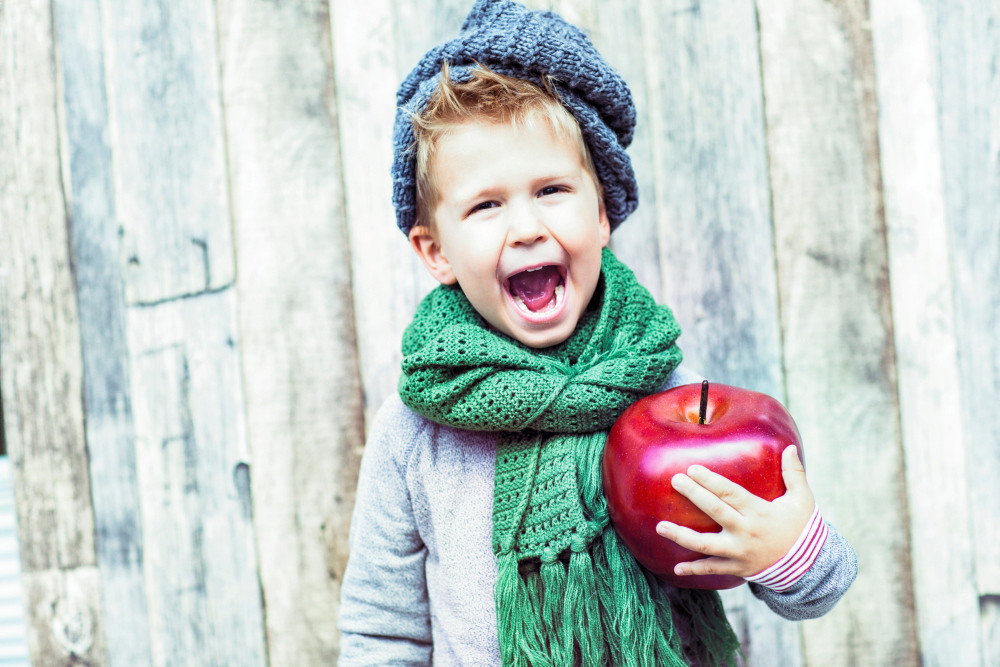 Junge mit übergroßem Apfel im Arm