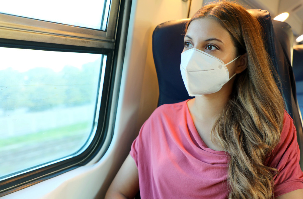 Frau mit FFP2-Maske sitzt im Zug