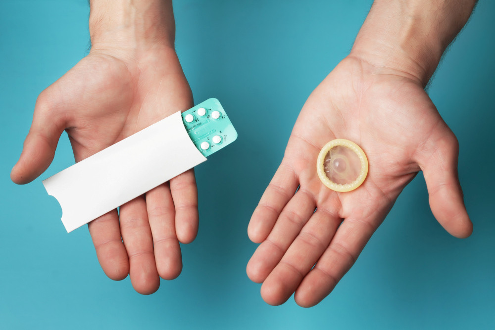 Kondom und Blisterpackung mit der “Pille” werden in die Kamera gehalten