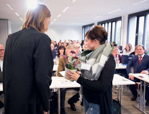 Frau Stephanie Rinsche von Blütenwerk Köln übergibt ein Blütenarragement, das beim Gewinnspiel gewonnen wurde.