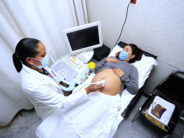 Schwangere Frau und Gynäkologin mit Mundschutz bei Ultraschalluntersuchung: 