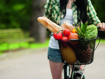 Frau mit Fahrrradkorb voller Obst und Gemüse