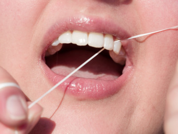 Nahaufnahme Mund: Frau benutzt Zahnseide