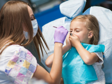 Kind hält sich Mund zu beim Zahnarzt