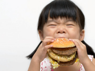 Kleines Mädchen beißt in Hamburger