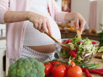 Schwangere bereitet Salat zu 
