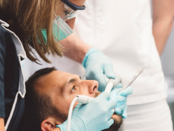 Zahnärztin untersucht Patient mit geöffnetem Mund