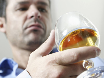 Mann blickt in einen Schwenker mit Cognac