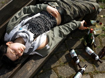 Gestelltes Symbolfoto: Mädchen liegt umringt von leeren Bierflaschen auf dem Boden