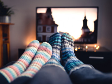 Paar mit Wollsocken auf dem Sofa vor dem Fernseher