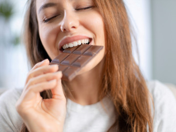 Junge Frau beißt in eine Schokoladentafel