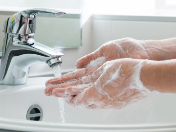 eingeseifte Hände am Waschbecken