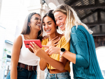Drei Frauen schauen auf ein Smartphone