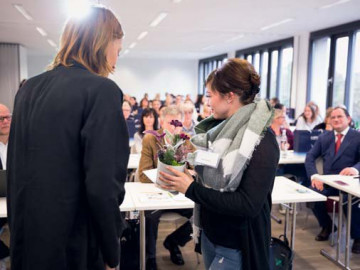 Frau Stephanie Rinsche von Blütenwerk Köln übergibt ein Blütenarragement, das beim Gewinnspiel gewonnen wurde.